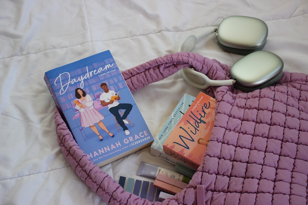 A copy of Daydream by Hannah Grace sits next to a purple bag and headphones.